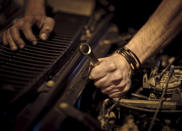 Technician working on a car engine with a wrench